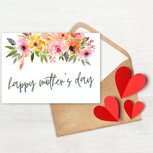 May include: A white card with a watercolor floral border and the text "happy mother's day" in black script. The card is sitting on a brown envelope with three red paper hearts.