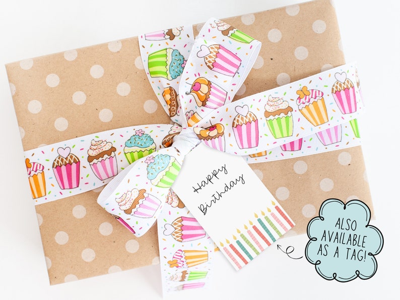 May include: A wrapped gift with a polka-dot brown paper and a white ribbon decorated with colorful cupcakes. A white tag with "Happy Birthday" is attached to the ribbon. The tag also has a row of colorful candles.