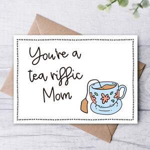 May include: A white card with black text that reads "You're a tea riffic Mom" and a cartoon illustration of a blue teacup with a tea bag.