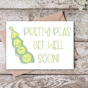 May include: A white greeting card with the text "Pretty Peas Get Well Soon!" in green and a cartoon pea pod illustration. The card is on a wooden surface with a brown envelope.