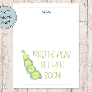 May include: A folded card, 5" x 7", with a light blue border. The card features a green pea pod illustration with smiling faces and the text "PRETTY PEAS GET WELL SOON!" in green. The card is on a light wood grain surface.