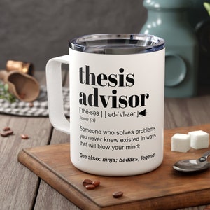 May include: White travel mug with the words "thesis advisor" in black. The mug includes a definition and related terms. The mug has a white handle and a silver rim. The mug is on a wooden cutting board.
