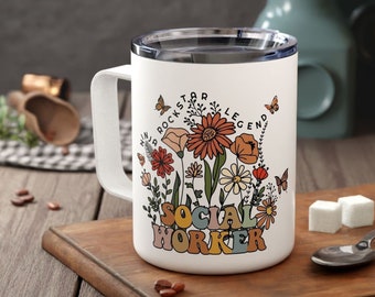 May include: White insulated coffee mug with a lid. The mug has a floral design with the text "Rockstar Legend Social Worker".