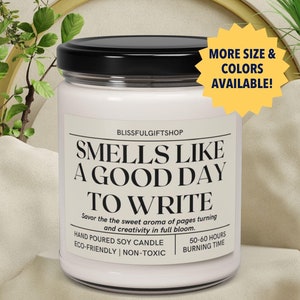 May include: A white soy candle with a black lid and the text "Smells Like A Good Day To Write" on the front. The candle is hand-poured, eco-friendly, non-toxic, and has a 50-60 hour burn time.