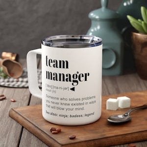 May include: White travel mug with a black and white design that says "team manager" and defines the word as "Someone who solves problems you never knew existed in ways that will blow your mind."  The mug also says "See also: ninja; badass; legend".