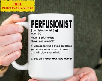 Può includere: Una tazza da caffè in ceramica bianca con una grafica nera che definisce la parola "perfusionista" come qualcuno che risolve i problemi in modi inaspettati. La tazza è tenuta dalle mani di una persona.