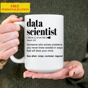 May include: White ceramic mug with a black graphic that reads "data scientist" and defines the term as "Someone who solves problems you never knew existed in ways that will blow your mind." The graphic also includes the phonetic pronunciation of the word "data scientist" and the phrase "See also: ninja; rockstar; legend".