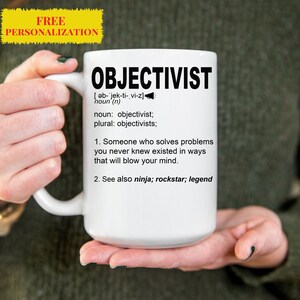 以下が含まれることがあります： 白いセラミック製のマグカップで、黒いデザインが施されています。"OBJECTIVIST"と書いてあり、その言葉は「あなたが存在を知っていたことのない問題を、あなたの心を吹き飛ばすような方法で解決する人」と定義されています。