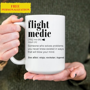 Puede incluir: Taza de cerámica blanca con un gráfico negro que dice "flight medic" y define el término como "alguien que resuelve problemas que nunca supiste que existían de maneras que te harán volar la mente." El gráfico también incluye la pronunciación fonética de la palabra "medic" y la frase "Ver también: ninja; rockstar; leyenda."
