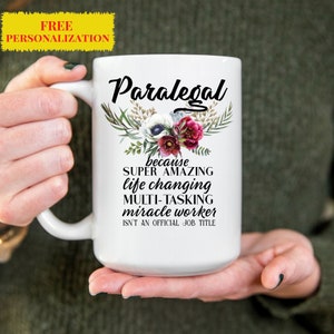 Könnte beinhalten: Weiße Keramiktasse mit Blumenmuster und dem Text "Paralegal because SUPER AMAZING life changing MULTI-TASKING miracle worker ISN'T AN OFFICIAL JOB TITLE"