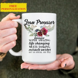 May include: White ceramic coffee mug with a floral design and the text "Loan Processor because SUPER AMAZING life changing MULTI-TASKING miracle worker ISN'T AN OFFICIAL JOB TITLE"