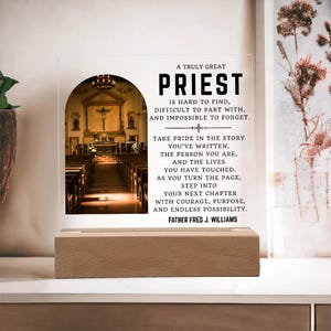 Può includere: Una targa in acrilico trasparente su una base rettangolare in legno. La targa presenta una fotografia ad arco di un interno di chiesa a sinistra e un testo nero a destra: A TRULY GREAT PRIEST IS HARD TO FIND, DIFFICULT TO PART WITH, AND IMPOSSIBLE TO FORGET. TAKE PRIDE IN THE STORY YOU'VE WRITTEN, THE PERSON YOU ARE, AND THE LIVES YOU HAVE TOUCHED. AS YOU TURN THE PAGE, STEP INTO YOUR NEXT CHAPTER WITH COURAGE, PURPOSE, AND ENDLESS POSSIBILITY. FATHER FRED J. WILLIAMS.