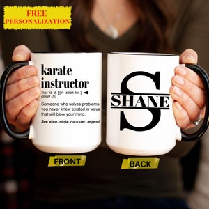 May include: White ceramic mug with a black handle. The front of the mug has the definition of the word "karate instructor". The back of the mug has a black letter "S" with the name "SHANE" written across the middle.