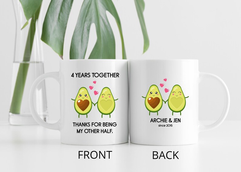 Puede incluir: Taza de cer&aacute;mica blanca con un gr&aacute;fico de dos mitades de aguacate que se toman de la mano con corazones en el medio. El texto en la parte delantera dice "4 Years Together Thanks for Being My Other Half." El texto en la parte posterior dice "Archie & Jen since 2015."
