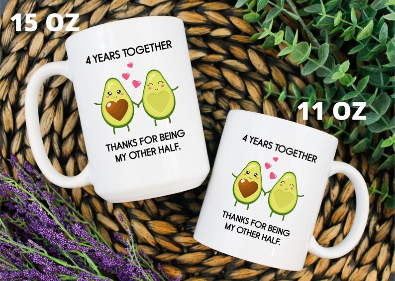 Puede incluir: Dos tazas de cer&aacute;mica blanca con un dise&ntilde;o de dos mitades de aguacate que se toman de la mano. El texto en las tazas dice "4 a&ntilde;os juntos" y "Gracias por ser mi otra mitad.". Las tazas est&aacute;n disponibles en tama&ntilde;os de 11 oz y 15 oz.