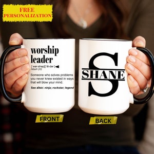 Puede incluir: Taza de cer&aacute;mica blanca con asa negra. La parte delantera de la taza tiene el texto "worship leader" con una definici&oacute;n y el texto "See also: ninja; rockstar; legend". La parte trasera de la taza tiene una gran letra negra "S" con el nombre "SHANE" escrito en el medio.