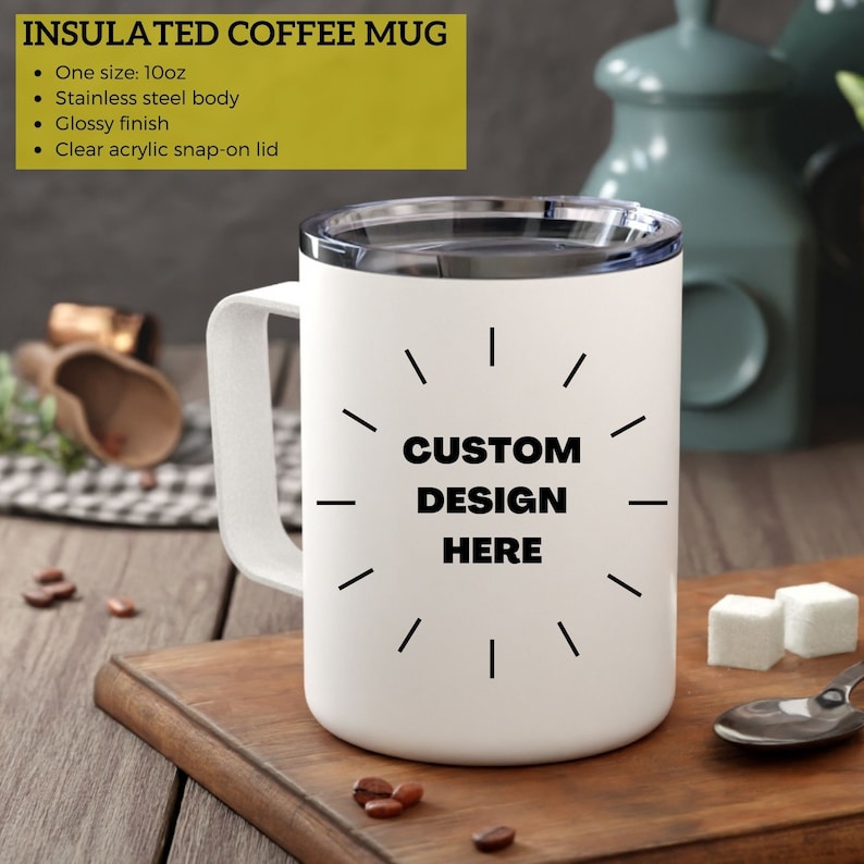 Puede incluir: Taza de caf&eacute; aislada blanca con tapa negra y un dise&ntilde;o negro que dice "CUSTOM DESIGN HERE" en la parte delantera. La taza est&aacute; sobre una superficie de madera.