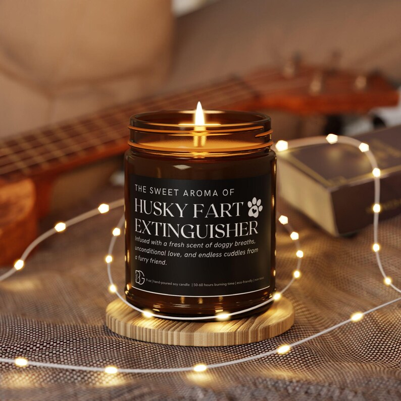 May include: A brown glass candle with a white label that reads "THE SWEET AROMA OF HUSKY FART EXTINGUISHER" and "Infused with a fresh scent of doggy breaths, unconditional love, and endless cuddles from a furry friend."
