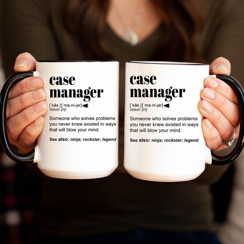 May include: Two white ceramic mugs with black handles and black rims. The mugs feature the text "case manager" with a definition and the words "ninja, rockstar, legend".