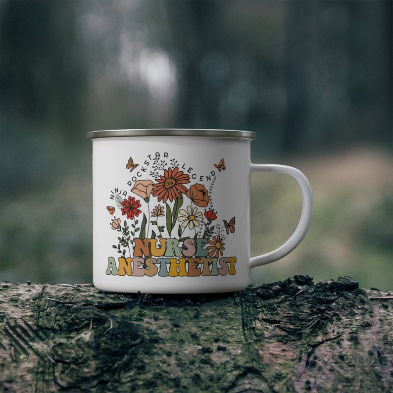Puede incluir: Taza de camping de esmalte blanco con un dise&ntilde;o floral y el texto "Ninja Rockstar Legend Nurse Anesthetist".