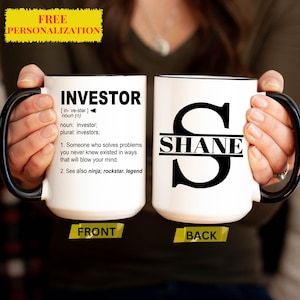 May include: White ceramic mug with a black handle and rim. The front of the mug has the word "INVESTOR" defined as "Someone who solves problems you never knew existed in ways that will blow your mind." The back of the mug has a black letter "S" with the name "SHANE" written across the middle.