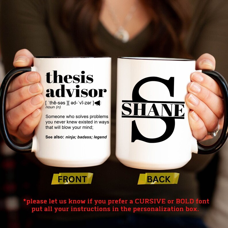 May include: White ceramic mug with black handle and rim. The front of the mug reads "thesis advisor" with a definition. The back of the mug has a large letter "S" with the name "SHANE" inside. The mug is held by a person.