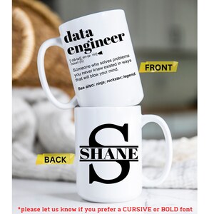 May include: Two white ceramic mugs stacked. The top mug features the text "data engineer" with a definition. The bottom mug displays the name "SHANE" with a large initial "S". The front and back of the mugs are labeled. The bottom of the image has text about font preference.