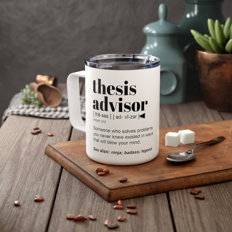 May include: White travel mug with the words "thesis advisor" in black. The mug includes a definition and related terms. The mug has a white handle and a silver rim. The mug is on a wooden cutting board.