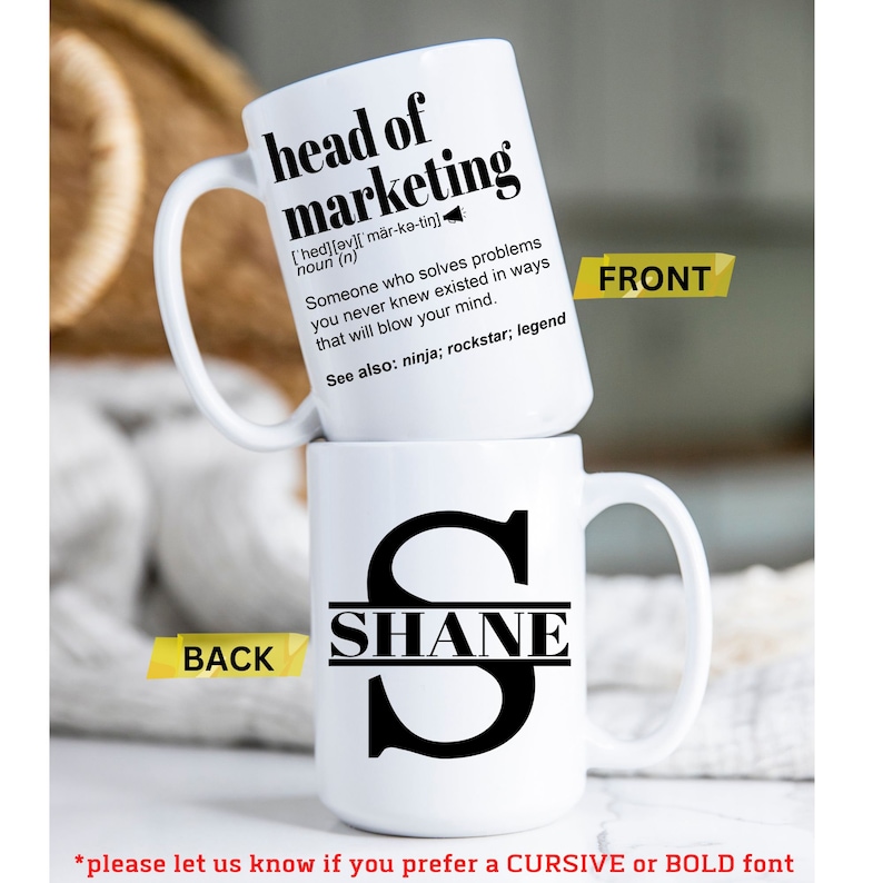 May include: Two white ceramic mugs stacked. The top mug reads "head of marketing" with a definition. The bottom mug features the name "SHANE" in a black font. The front of the top mug is labeled "FRONT" and the back of the bottom mug is labeled "BACK".
