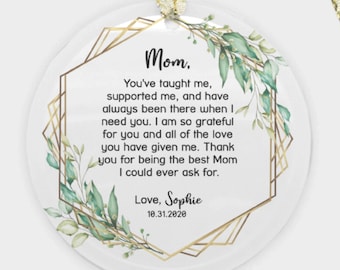 May include: A white round bauble with a gold geometric frame and green leafy branches. The bauble has a message that reads "Mom, You've taught me, supported me, and have always been there when I need you. I am so grateful for you and all of the love you have given me. Thank you for being the best Mum I could ever ask for. Love, Sophie 10.31.2020"