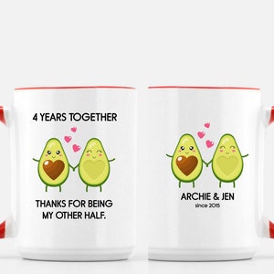 Puede incluir: Dos tazas de cer&aacute;mica blanca con asas rojas. Una taza tiene el texto "4 Years Together" y "Thanks for being my other half." con una imagen de dibujos animados de dos aguacates tom&aacute;ndose de la mano. La otra taza tiene el texto "Archie & Jen since 2015" con una imagen de dibujos animados de dos aguacates tom&aacute;ndose de la mano.