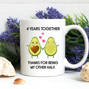 Puede incluir: Taza de cer&aacute;mica blanca con un gr&aacute;fico negro de dos mitades de aguacate que se toman de la mano. Los aguacates tienen caras y corazones. El texto en la taza dice "4 Years Together Thanks for being my other half."