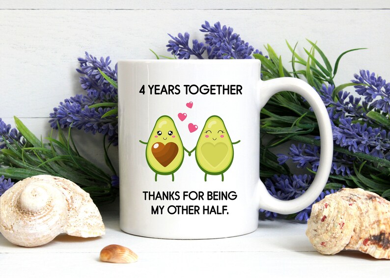 Puede incluir: Taza de cer&aacute;mica blanca con un gr&aacute;fico negro de dos mitades de aguacate que se toman de la mano. Los aguacates tienen caras y corazones. El texto en la taza dice "4 Years Together Thanks for being my other half."
