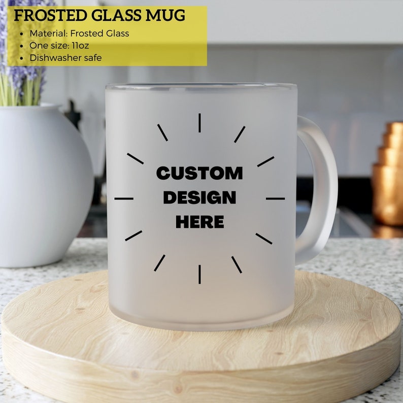 May include: Frosted glass mug with a handle. The mug has the text "CUSTOM DESIGN HERE" in black. The mug is sitting on a wooden surface. The mug is 11oz.
