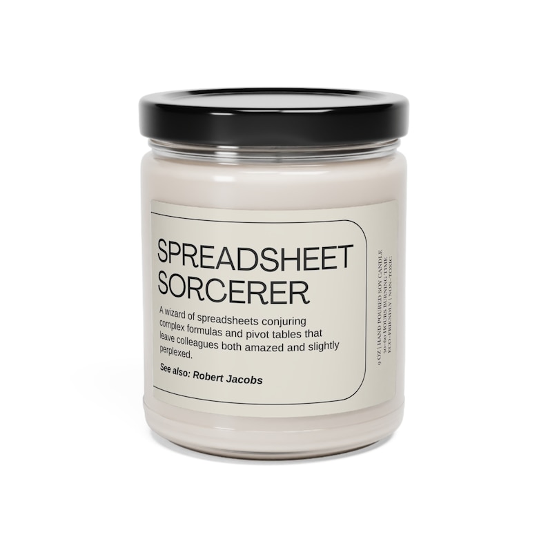 May include: A white soy candle in a glass jar with a black lid. The label reads "SPREADSHEET SORCERER" and describes the candle as "A wizard of spreadsheets conjuring complex formulas and pivot tables that leave colleagues both amazed and slightly perplexed." The label also says "See also: Robert Jacobs".