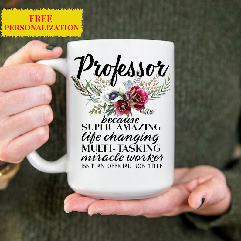 Op de afbeelding: Een witte keramische koffiemok met een bloemenmotief en de tekst "Professor because SUPER AMAZING life changing MULTI-TASKING miracle worker ISN'T AN OFFICIAL JOB TITLE"