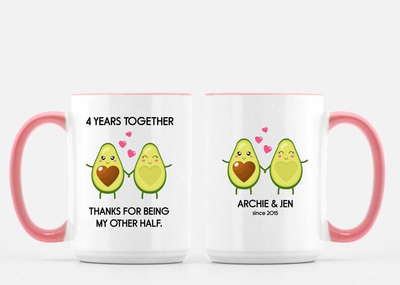 Puede incluir: Taza de cer&aacute;mica blanca con borde y asa rosa. La taza presenta un gr&aacute;fico de dos mitades de aguacate que se toman de la mano con corazones en el medio. El texto en la taza dice "4 Years Together" y "Thanks for being my other half." El otro lado de la taza tiene el texto "Archie & Jen since 2015".