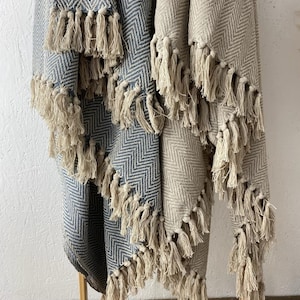 May include: Two woven blankets with fringe, one in a blue and white herringbone pattern and the other in a beige and white herringbone pattern.