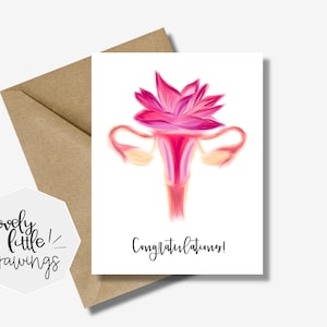 May include: A greeting card with a watercolor illustration of a stylized female reproductive system in shades of pink and red. The card reads "Congratulations!" in black script. The card is placed on a brown envelope.