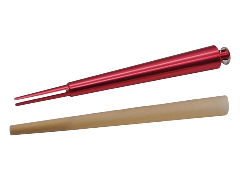 Puede incluir: Una herramienta de metal roja con dos puntas y una peque&ntilde;a perilla en el extremo. La herramienta se utiliza para empacar un cono. Tambi&eacute;n se muestra un cono de papel marr&oacute;n.