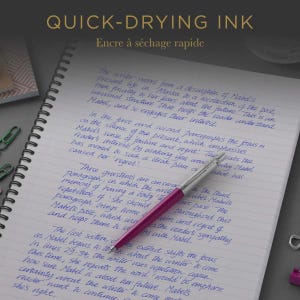 May include: A magenta ballpoint pen with a silver clip and tip rests on a spiral-bound notebook featuring blue ink handwriting. The text "QUICK-DRYING INK" is visible at the top of the image, along with several small green paper clips.