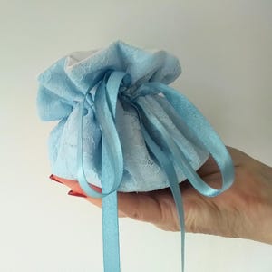 TRAVEL JEWELLERY POUCH in a pale blue lacy fabric with a large central area for necklaces etc and eight smaller sections