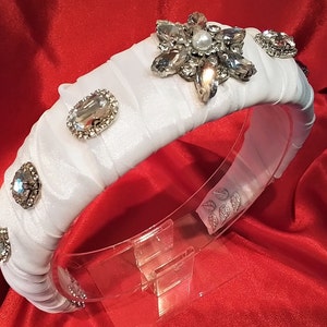 A WIDE BRIDAL HEADBAND in a white fabric with a large central diamante &#39;star&#39; plus three &#39;gems&#39; in descending sizes