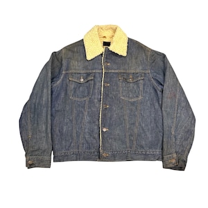 Op de afbeelding: Een blauw spijkerjack met een crème-kleurige, met sherpa gevoerde kraag. De jas heeft twee borstzakken, knoopsluitingen en een klassiek ontwerp. De jas is van medium wassing denim.