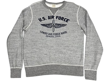 May include: A grey crew neck sweatshirt featuring the text "U.S. AIR FORCE" above a propeller and wings graphic. Below the graphic is the text "LOWRY AIR FORCE BASE DENVER, COLO." The sweatshirt has white stitching and a grey ribbed hem and cuffs.