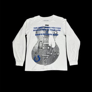 May include: White long-sleeve shirt featuring a gray guitar graphic. The shirt has blue text that reads "THE ONLY THING YOU CAN REALLY FRESHEN YOUR LIFE" and "NIGO'S FAVORITE SHOP". The shirt is made of cotton base material.