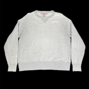 Può includere: Una felpa grigio chiaro con girocollo e maniche lunghe. La felpa ha uno scollo a V e polsini e orlo a coste. Una piccola etichetta rossa è visibile vicino allo scollo. L'indumento è realizzato in un materiale morbido e confortevole.