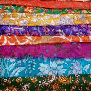 May include: A stack of colorful fabric scraps with floral patterns. The fabric is arranged in a rainbow pattern, with red, orange, yellow, green, blue, and purple fabrics.