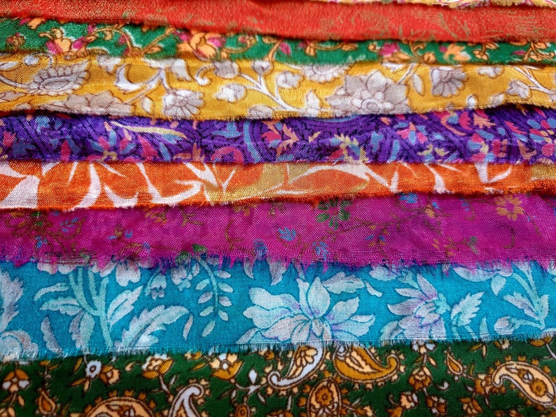 May include: A stack of colorful fabric scraps with floral patterns. The fabric is arranged in a rainbow pattern, with red, orange, yellow, green, blue, and purple fabrics.