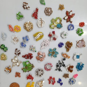 May include: Assortment of colourful beaded embellishments in various shapes and sizes, including flowers, leaves, stars, and geometric designs. The embellishments are made of small beads and sequins.